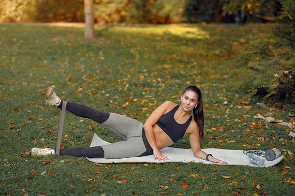 Chica deportiva en un entrenamiento negro en un parque de otoño — Foto de Stock