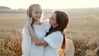 Anne ve kızı buğday tarlasında sarılıp eğleniyorlar.