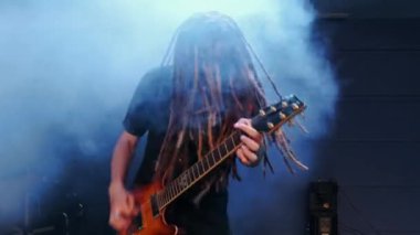 Gitarist sahnede elektro gitarını dumanla çalıyor.