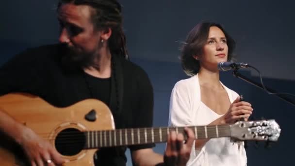 Vrouwelijke zangeres met tamboerijn en muzikant die gitaar speelt op het podium — Stockvideo