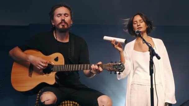 Vrouwelijke zangeres met shaker en muzikant die gitaar speelt op het podium — Stockvideo