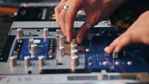 Close up de DJ mãos controlando uma mesa de música em um clube noturno — Vídeo de Stock