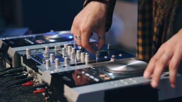 Primer plano de manos de DJ controlando una mesa de música en un club nocturno — Vídeo de stock