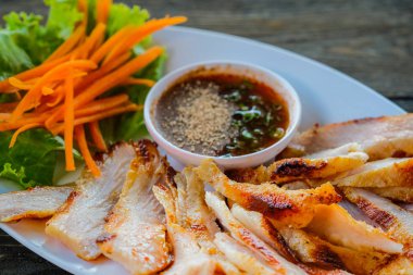 Sebze ve sos ahşap bir masa üzerinde daldırma ile beyaz bir tabak ızgara domuz.