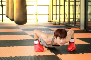 Spor salonunda adamın kırmızı boks eldivenleri ittirir.