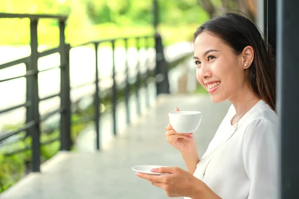 Young woman drinking hot coffee in sidewalk cafe