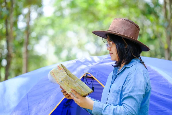 Mujer buscando un camino con mapa y reloj en el bosque —  Fotos de Stock