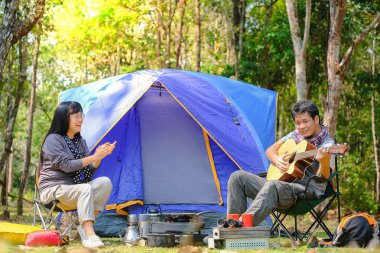 Asya genç gitar açık mavi tuval kamp çadır oynarken 
