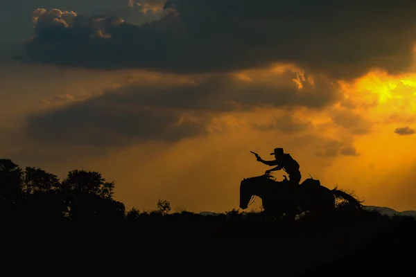 Silueta de vaquero en un caballo durante el atardecer — Foto de Stock