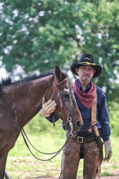 Egy cowboy ruhás férfi a lovával. — Stock Fotó