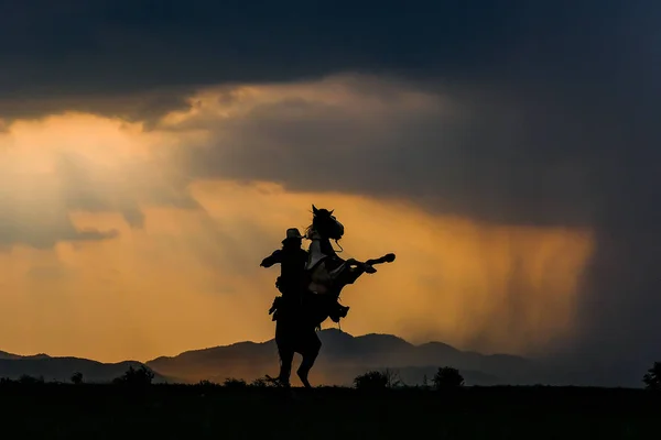 Um homem de fato de cowboy com o seu cavalo — Fotografia de Stock