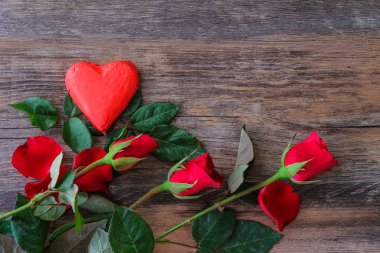 Kırmızı kalp şeklinde çikolata ve gül ahşap zeminler üzerine yerleştirilen bir