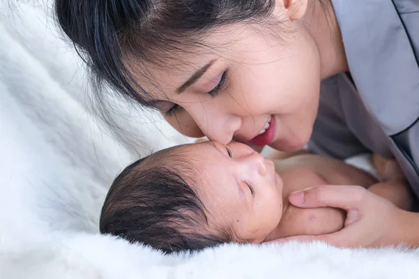 En småbarn i en ömsint omfamning av mor vid fönstret — Stockfoto