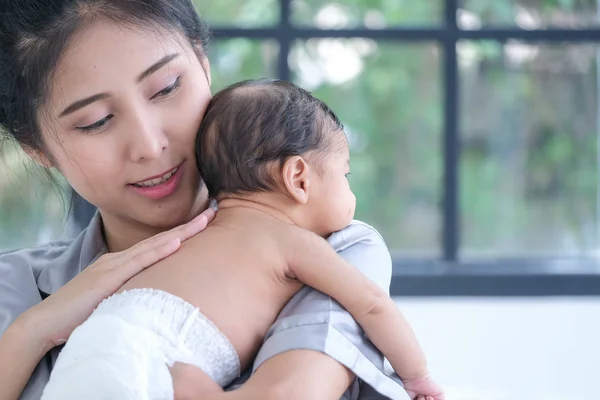 Азиатская мать держит 1,5-месячного ребенка, склоняясь над ее sho — стоковое фото