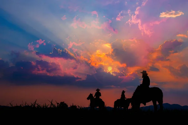 Cowboy a cavalo com vista para as montanhas e o pôr do sol s — Fotografia de Stock