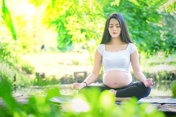 Mujer embarazada haciendo ejercicio de yoga en la naturaleza en un verano — Foto de Stock