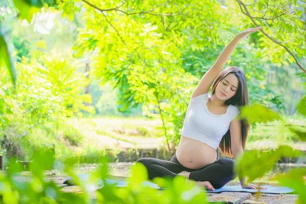 Mujer embarazada haciendo ejercicio de yoga en la naturaleza en un verano — Foto de Stock