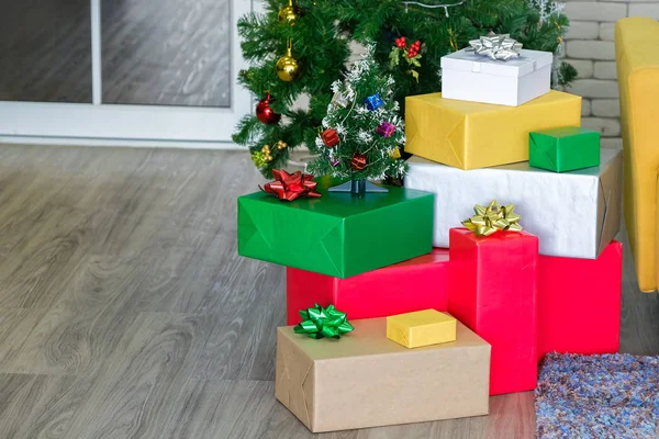 Beautiful Christmas gift boxes on floor near fir tree in room — Stock Photo, Image