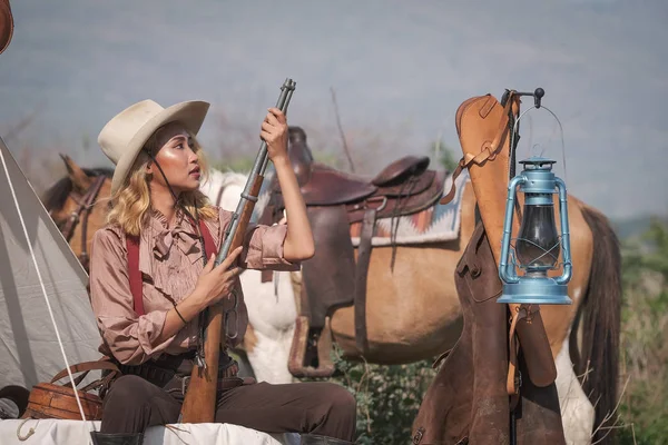 A beautiful Asian cowboy who takes care of her gun and horse wit — ストック写真