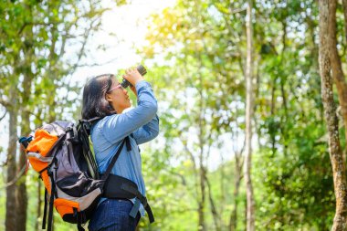 Yürüyüşçü adam dürbünle bakıyor. Manzaranın tadını çıkarıyor.