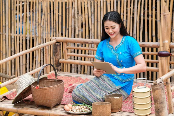 Native woman in the northeast of Thailand in blue dress and technology in the present era