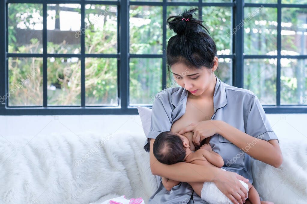 A 2 month old Asian baby is happy to suck breast milk.