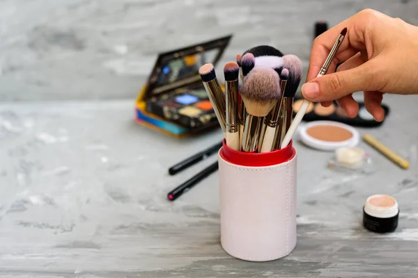 Professional makeup brushes and tools on grey background