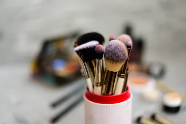 Professional makeup brushes and tools on grey background