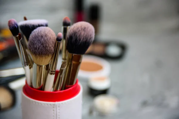 Professional makeup brushes and tools on grey background