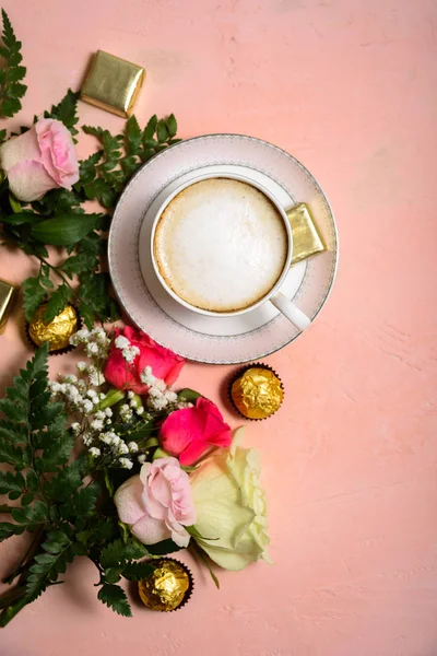 Cup of coffee with flowers on pink