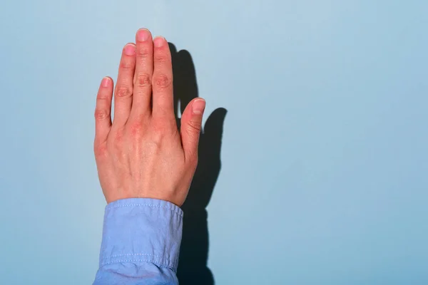 Left hand of woman. Left hander day concept. In blue shirt. Hard light and shadow