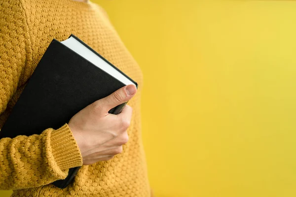 Woman student in sweater with books on yellow