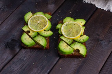 koyu ahşap arka plan üzerinde avokado ile sandviç