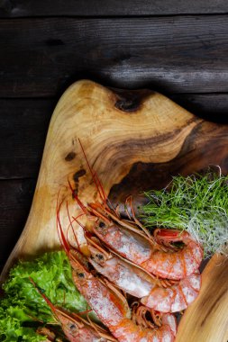 Tahtada kaynamış kral karidesleri, siyah ahşap bir masada.