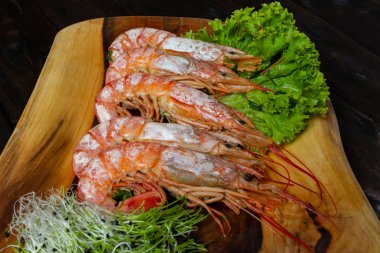 Tahtada kaynamış kral karidesleri, siyah ahşap bir masada.