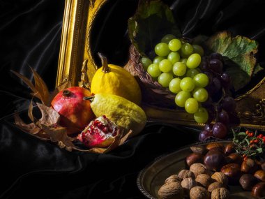 Taze meyve ve sebze ile natürmort. Üzüm, nar, sarı kavun, sarı kabak, ceviz, kestane. Siyah arka plan. Altın Çerçeve.