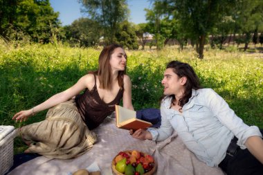 Birkaç genç insanlar, erkek ve kadın, bir piknik park çim yalan. O ona dinler iken bir kitaptan bazı ayetler okur. Kız, hafif cilt, mavi gözlü, esmer. Çocuk, hafif cilt, uzun siyah saçlı.