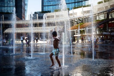 Milan, İtalya - 29 Ağustos 2015: Çocuk eğlenin Piazza Gae Aulenti ferahlık yaz sıcağında arıyorum, çeşmeler içinde banyo.