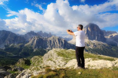 Güzel alp sahne dalmış, bir adam bir resim cep telefonu ile yüksek irtifa peyzaj dağ zirveleri ve bulutlu gökyüzü ile alır.