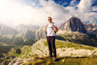 Güzel alp sahne içinde yer alan bir adam dağ zirveleri ve bulutlu gökyüzü ile yüksek irtifa manzara hayran. Bir uzun yürüyüşe çıkan kimse Dolomites'in üst kısmında. Gün batımında dağ doruklarına dağ manzarası arka planda.