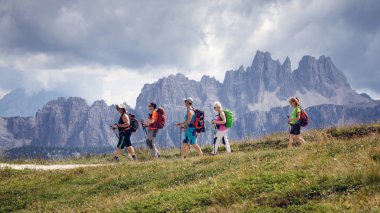 Cortina d'Ampezzo, İtalya - 18 Ağustos 2018: yürüyüş yapan bir grup dağ yolu üzerinde yürür. Bir yaz günü bulutlu gökyüzü ile. Arka planda, dolomites (Croda da Lago doruklarına).