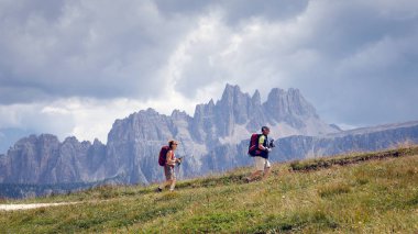 Cortina d'Ampezzo, İtalya - 18 Ağustos 2018: yokuş yukarı dağ yolda yürüme yürüyüş yapan bir çift. Bir yaz günü bulutlu gökyüzü ile. Arka planda, dolomites (Croda da Lago doruklarına).