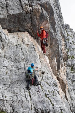 Cortina d'Ampezzo, İtalya - 17 Ağustos 2018: bir erkek ve bir kadın çıplak elle ve halatlar, kayalık bir duvar üstüne tırmanmaya. Adam bir mesafeden eliyle selamlıyor. Konumu Cinque Torri, Dolomites.