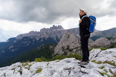 Güzel alp sahne içinde yer alan bir adam dağ zirveleri ve bulutlu gökyüzü ile yüksek irtifa manzara hayran.