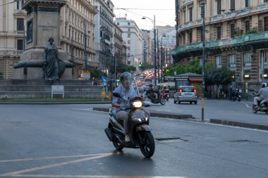 Şehir trafiğinde scooter kullanan bir adam.