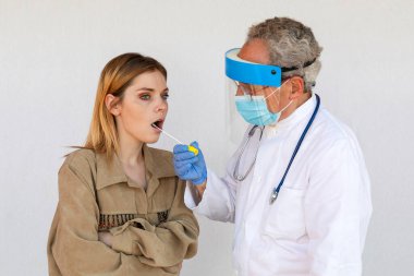 Doktor, salgının yayılmasına neden olan SARS-CoV-2 virüsünü araştırmak için genç bir kadının boğazından örnek aldı..