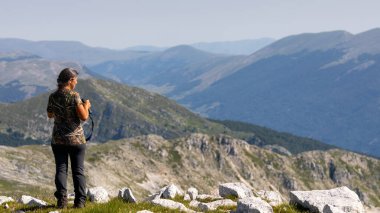 Zirvedeki yürüyüşçü bir teleskopla çevreyi inceliyor..