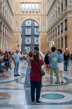 Naples, Italy - September 12, 2025: A girl takes a photo of the architecture of the magnificent Galleria Umberto I in the city's historic center with her cell phone.