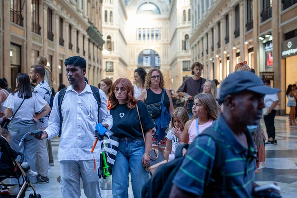 Naples, Italy - September 12, 2025: A street vendor offers chargers and other items to tourists strolling by the entrance to the majestic Galleria Umberto I, a historic monument.
