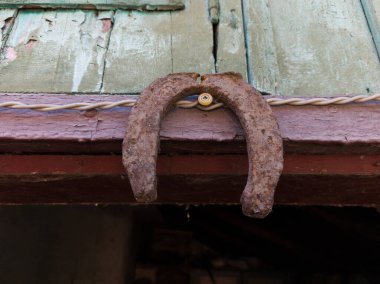 Ahşap bir binanın kenarında asılı paslı bir at nalı..